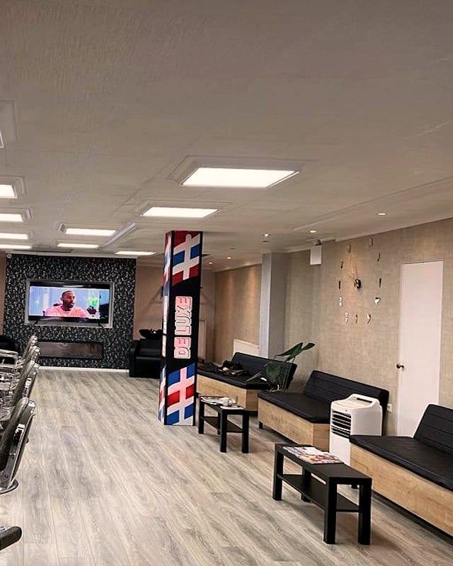 De lange zaak met een rij chromen barberstoelen en houten werkplekken